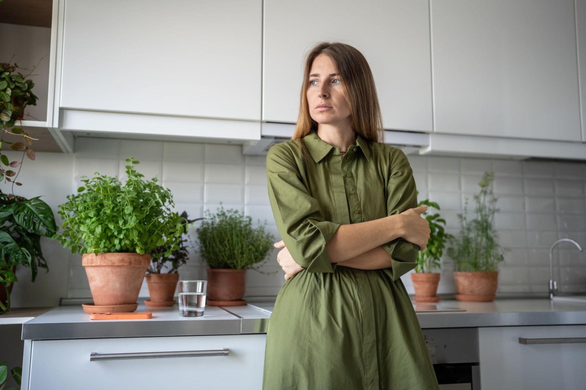 Eftertænksom kvinde i sit køkken overvejer gæld og økonomi – står med en vigtig beslutning om gældssanering
